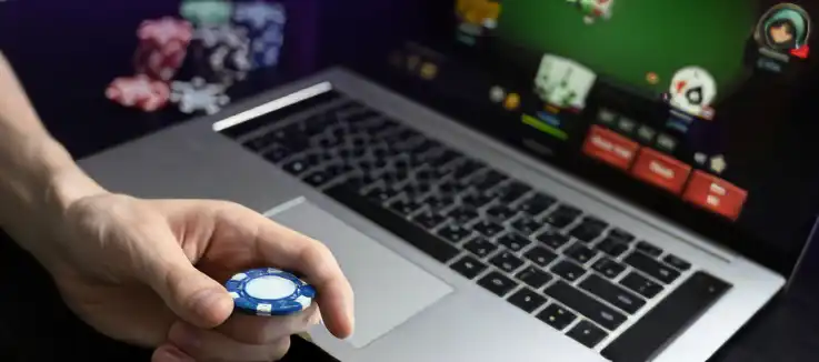laptop screen displaying a card game with a player holding a chip looking at the screen 