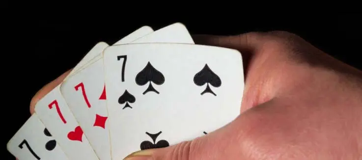 poker hand showing 4 sevens and cash on the table