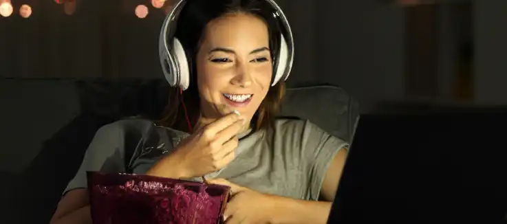 woman with a bowl of popcorn watching a movie online 